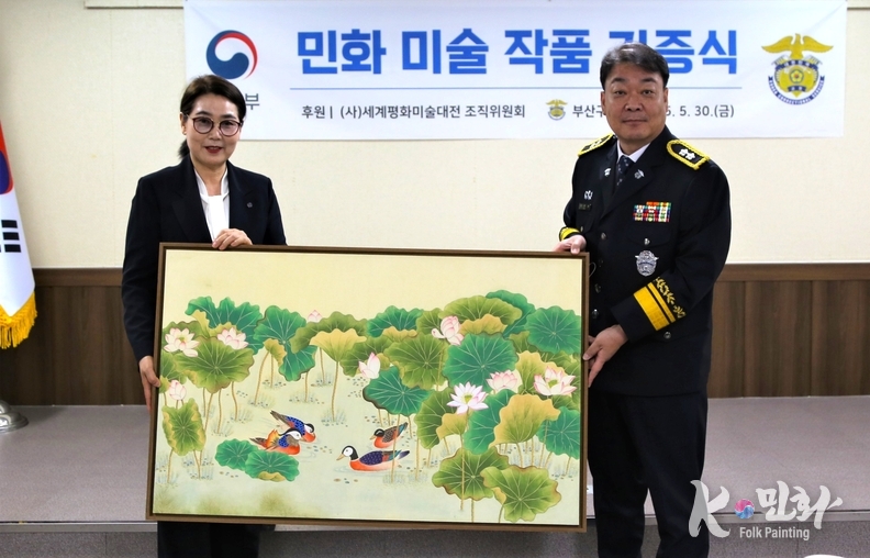 K-민화연구소 이미형 소장, 명지대 K-민화학과 교수(좌측)가 남준락 부신구치소장(우측)에게 전달하고 있다.