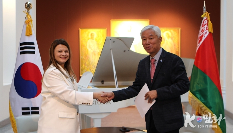  벨라루스 국립미술관장(좌측)과 외교저널 회장 이존영(우측)이 K-민화 작품 32점 기증 증서를 교환한 뒤 악수하고 있다.